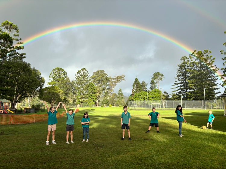 Students standing under a beautiful rainbow at the risk public school