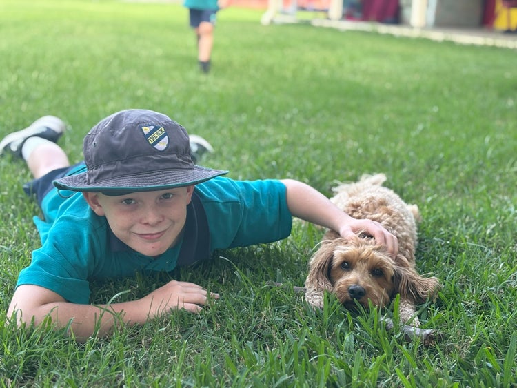 Student lying on the grass with the support dog miss honey