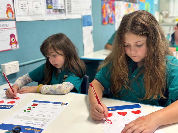 a primary and an infant student working together in class
