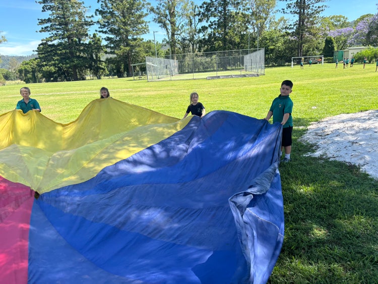 students playing with the big colourful parachute